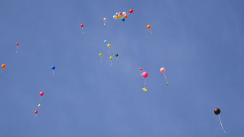 Low angle view of balloons flying against sky