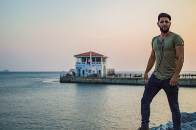 Portrait of man standing by sea against sky during sunset