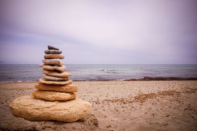 Stack of stones on beach against sky