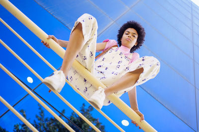 Low angle view of young woman standing against blue sky