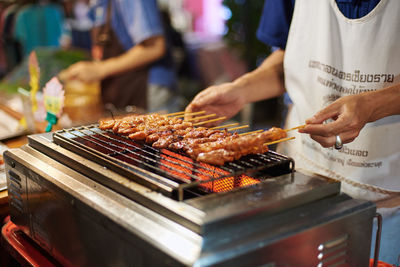 Midsection of man preparing food on barbecue grill