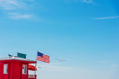 Low angle view of flag flying by building against sky