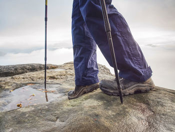 Man hiker legs stand on mountain peak rock. slippery journey at the edge