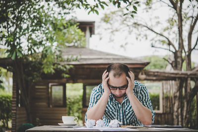 Stressed man with crumpled paper balls on table