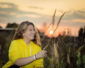A young girl on a meadow with tall grass in the rays of the setting sun.