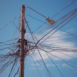 Low angle view of power lines against blue sky