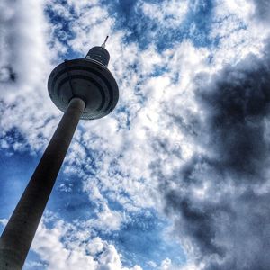 Low angle view of communications tower against cloudy sky