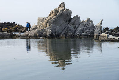 Reflection of rocks in sea against clear sky