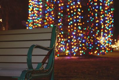 Close-up of empty bench against illuminated lights