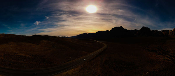 Scenic view of road by mountains against sky