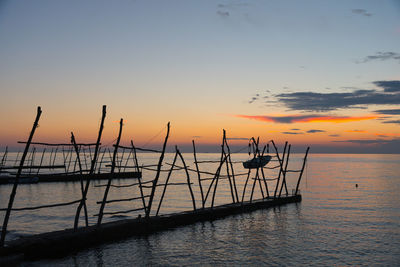 Silhouette fishing boat in sea against sky during sunset