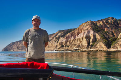 Full length of man standing on mountain against clear blue sky