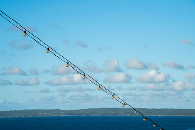 Fishing rod by sea against sky