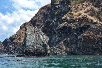 Rock formations by sea against sky