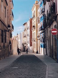 People walking on footpath amidst buildings in city