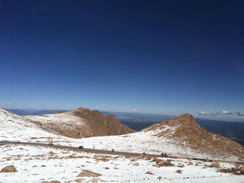 Scenic view of snow covered mountains against blue sky