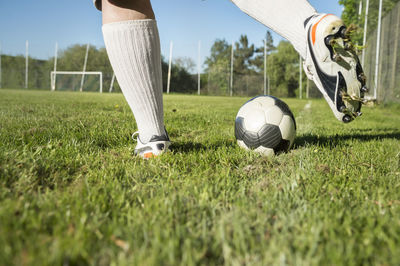 Low section of person playing soccer on grassy field