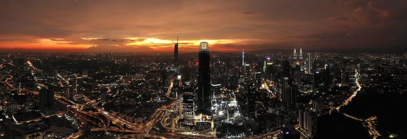 Illuminated cityscape against sky during sunset