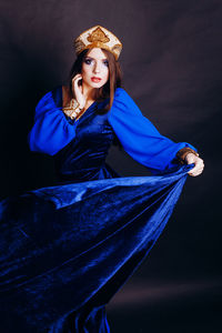 Portrait of beautiful woman in traditional clothing standing against black background