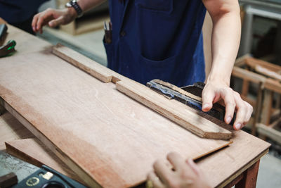 Midsection of carpenter making furniture in carpentry workshop