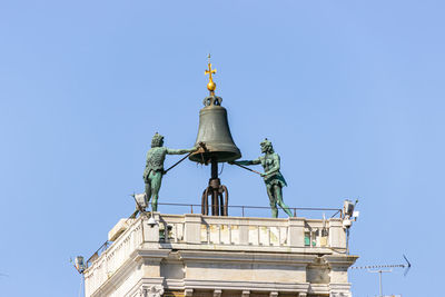 Low angle view of statue against building against clear sky