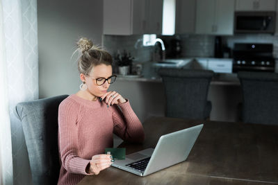 Young woman using phone while sitting on table