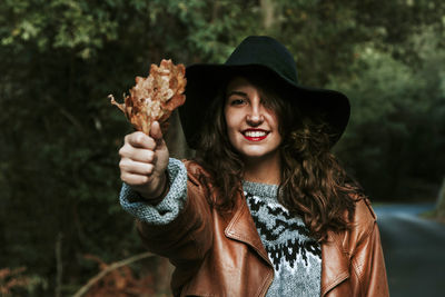 Portrait of smiling young woman holding hat