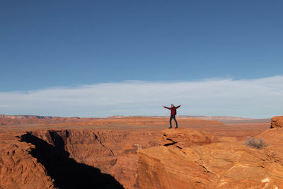 Young man opening arms in the form of freedom at horseshoe bend in the grand canyon, arizona, usa