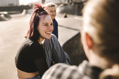 Smiling teenage girls sitting in skatepark