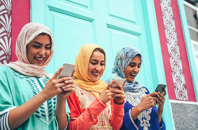 Smiling women using mobile phone at entrance