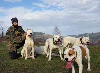 Military man with dogs on field against sky