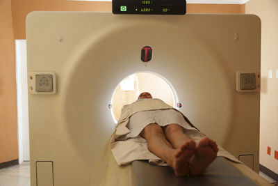 Patient lying at entrance of cat scan machine in medical examination room