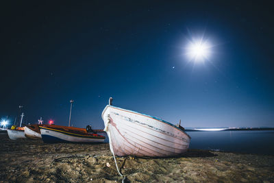 Boat moored on beach against sky at night