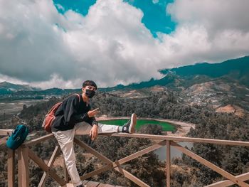 Man standing on railing against mountains