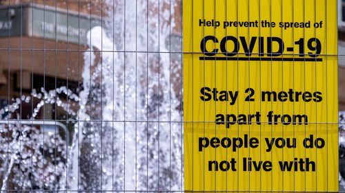 Covid-19 pandemic warning sign in inner city by a blocked off fountain