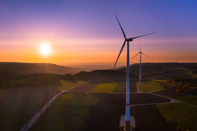 Aerial view of colorful autumn sunset beyond wind turbines