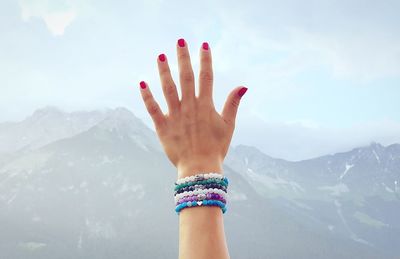 Midsection of person hand on snowcapped mountain against sky