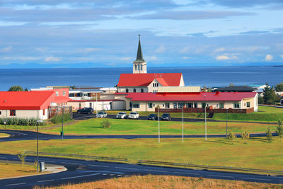 Built structure on field by sea against sky