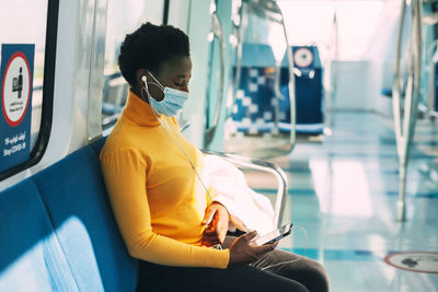 A young african woman in a protective mask rides the subway 