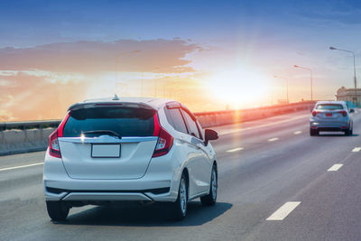 Cars on road against sky during sunset