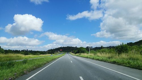 Road amidst field against sky