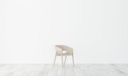 Empty chair against white wall