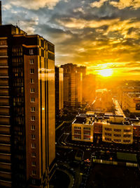 Modern buildings in city against sky during sunset