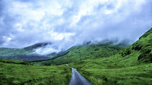 Road amidst green landscape against sky