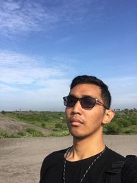 Portrait of young man wearing sunglasses against sky