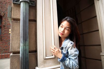 Portrait of smiling girl standing against window