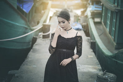 Female model in black dress standing at harbor