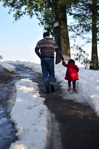 Rear view of people walking on snow covered landscape