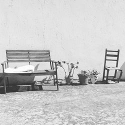 Empty chairs and table against wall