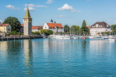 Sailboats in canal by buildings against sky